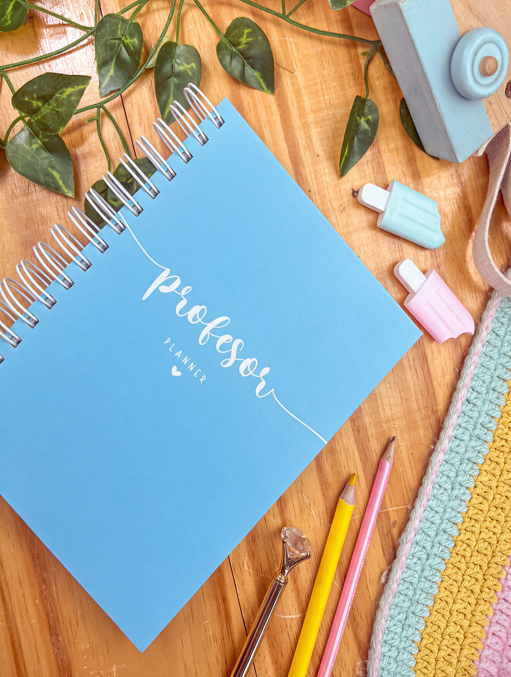 Agenda docente de anillas con portada azul y la palabra «profesor planner» en blanco, sobre una mesa de madera con lápices