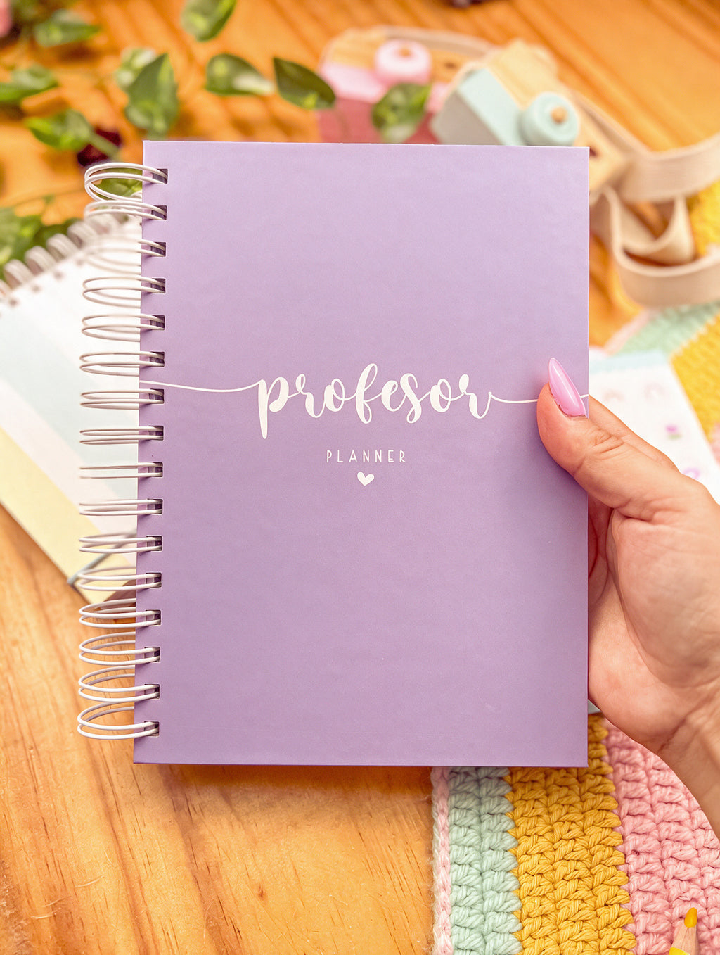 Agenda docente de anillas con portada lila y la palabra «profesor planner» en blanco, sostenida en la mano