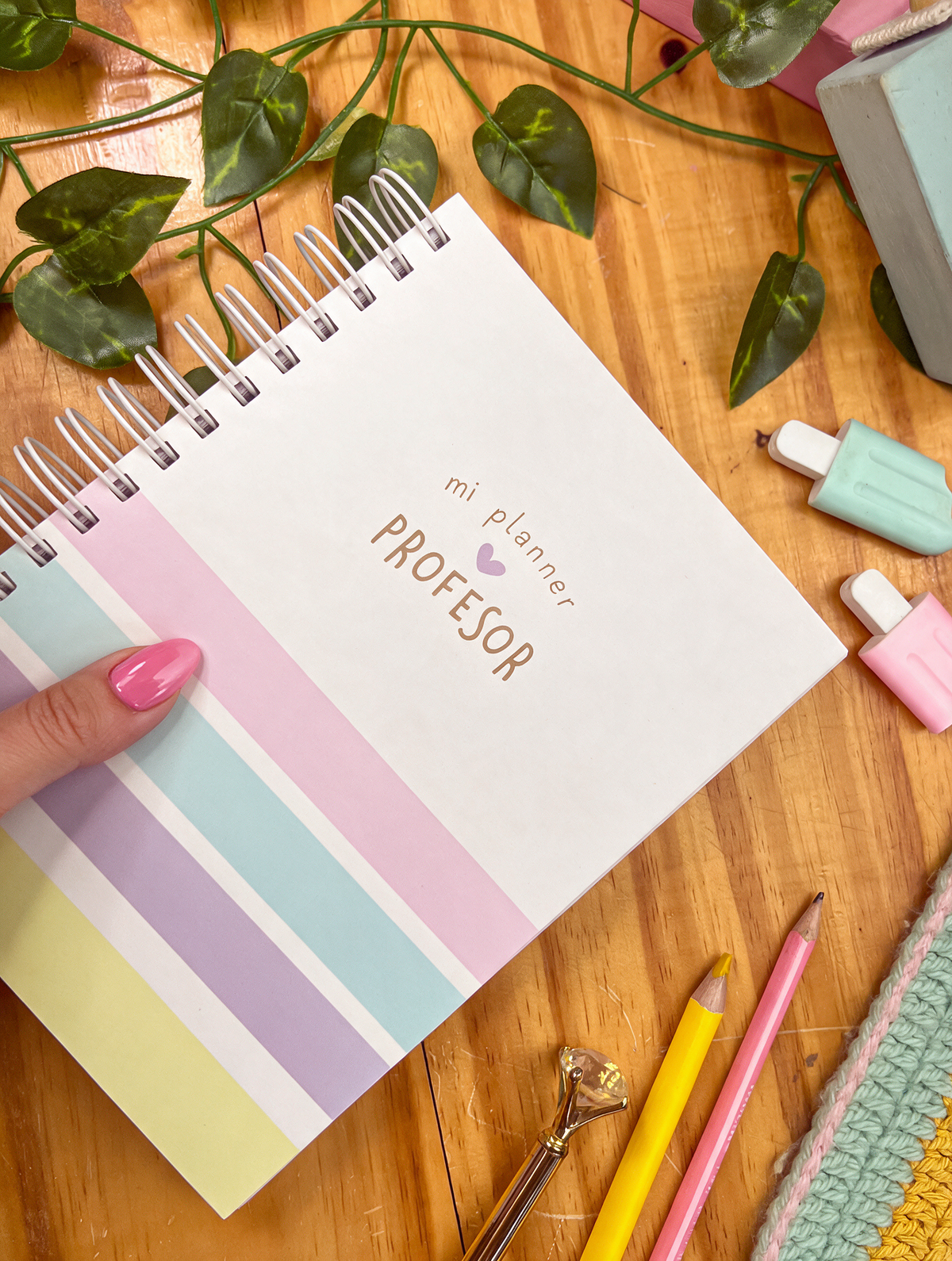 Planificador docente de anillas con portada «mi planner profesor» y rayas pastel rosa, azul, lila y amarillo, sostenido en la mano